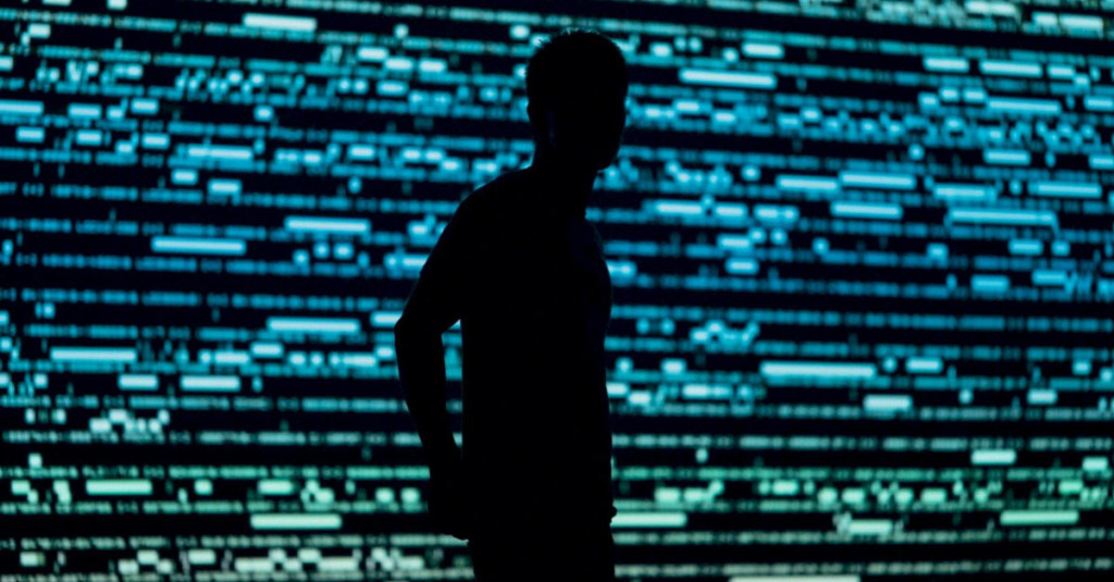 A menacing hacker silhouetted against a blue, green, and black digital background